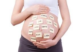 Baby names on her belly. Cropped image of pregnant woman with baby names on her belly standing isolated on white