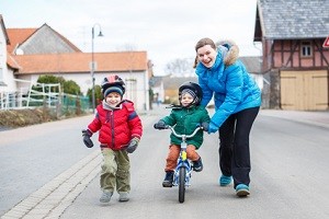Young mother teaching her 2 years old little son to ride a bike