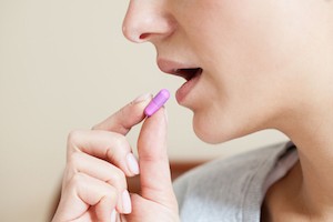 Close-up of woman taking pill