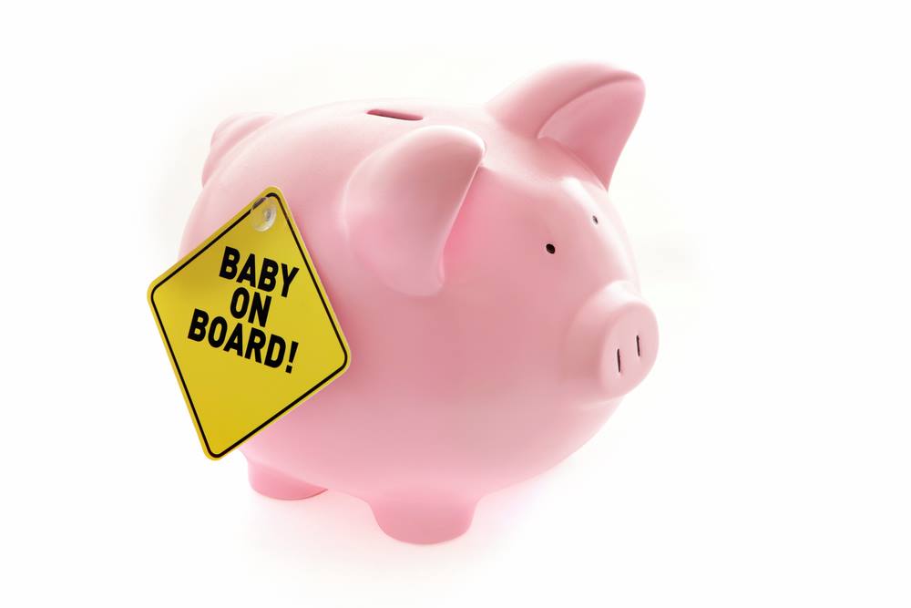 Pink piggy bank showing baby on board sign to reflect having a baby on a budget